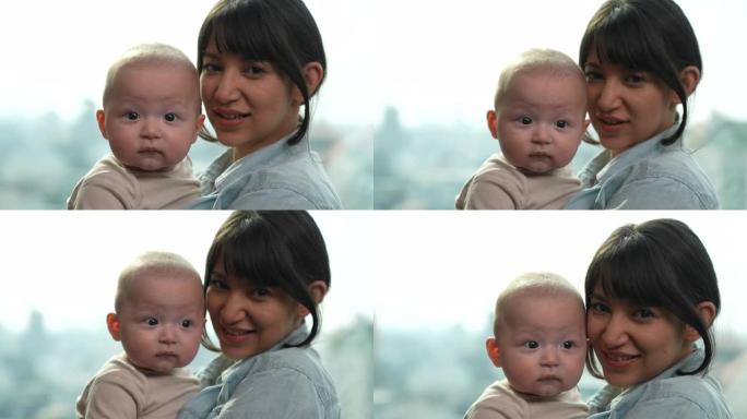 一位美丽的年轻母亲正慈爱地抱着她6个月大的婴儿。她与儿子爱玩，看着相机。