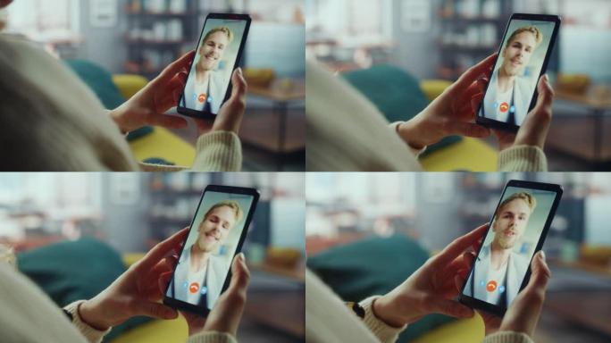 一名女性在客厅的智能手机上与她英俊的白人男性朋友在视频通话中聊天的特写镜头。自由职业者通过互联网与办