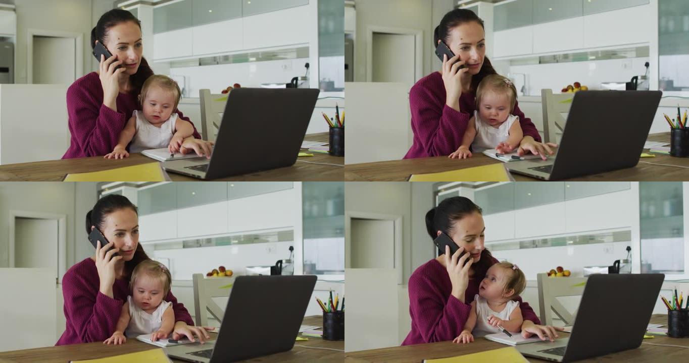 白人母亲在家中工作时抱着婴儿在智能手机上聊天并使用笔记本电脑