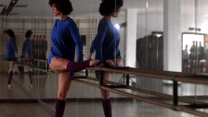 非裔美国妇女在舞蹈工作室的芭蕾舞上伸展身体