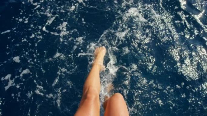 4k视频片段，一个无法识别的女人在意大利度假期间坐在船上踢水