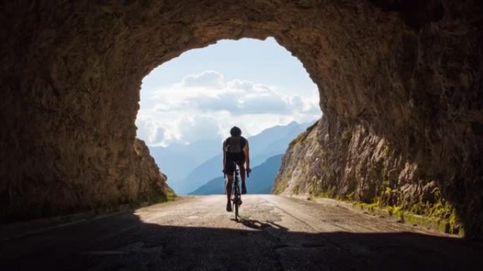 公路骑自行车的人骑在山路上，穿过岩石隧道