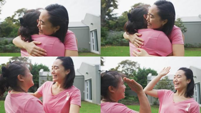 快乐的亚洲母亲和成年女儿在花园里拥抱和击掌，穿着粉色t恤