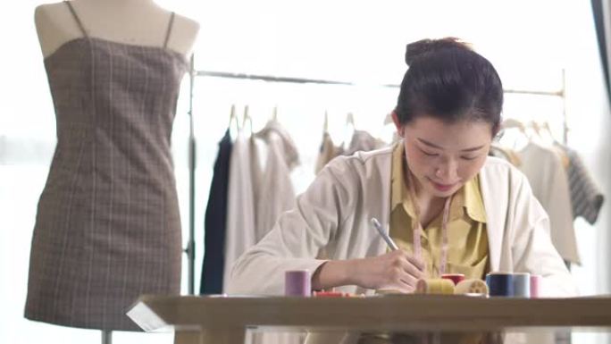 年轻的亚洲时装设计师在家庭工作室工作; 小企业概念