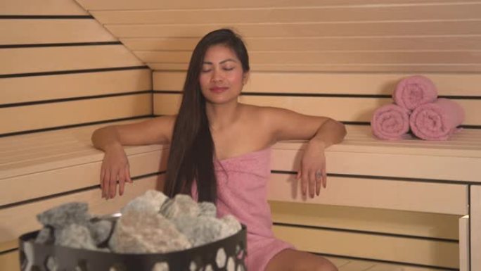 特写: 加热器岩石与美丽的女人在芬兰桑拿浴室的长凳上放松