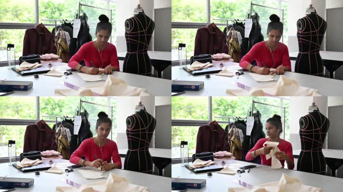 亚洲印度女性时尚大学生在大学工作坊剪布面料做服装项目