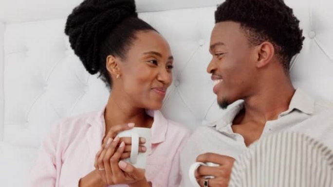 早上在家，对来自非洲的一对黑人夫妇的咖啡、床上放松和爱的心态感到满意。男人和女人在房屋卧室里交谈，交