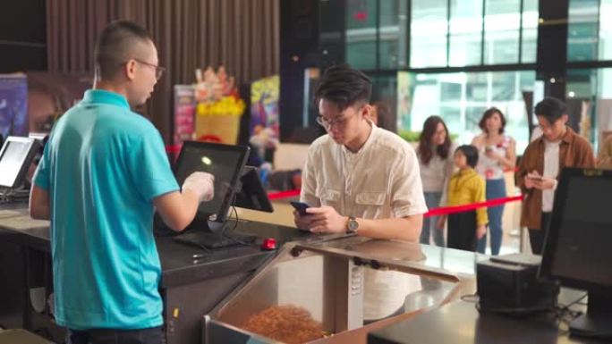 亚洲华裔青少年成人在电影院电影放映时间前购买电影票，爆米花和饮料