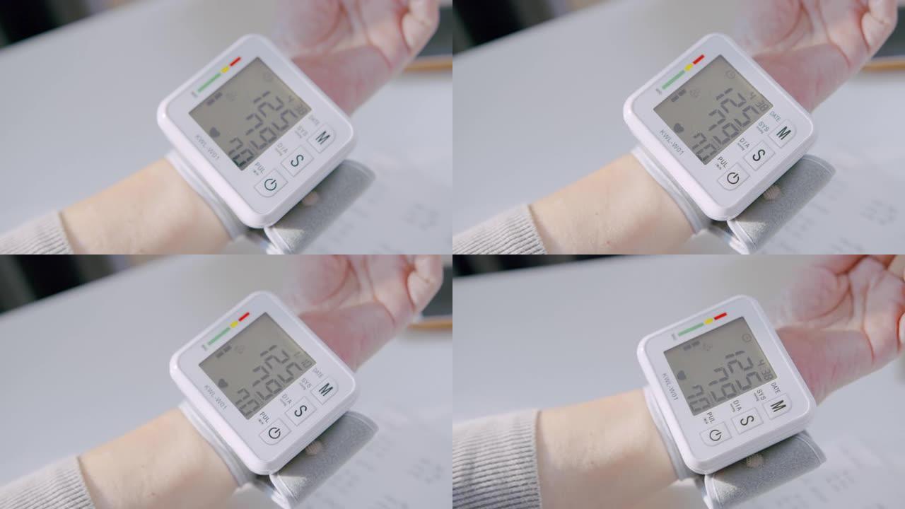 高级成人腕部监护仪检查血压在笔记本上记录她的血压数字