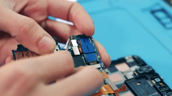 修理工用镊子把微芯片切成碎片。手特写。