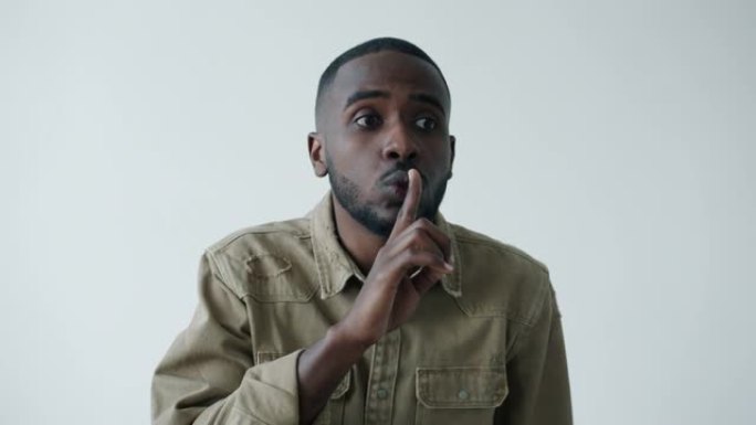 严肃的年轻非洲裔美国人要求用手指触摸嘴唇的沉默的肖像