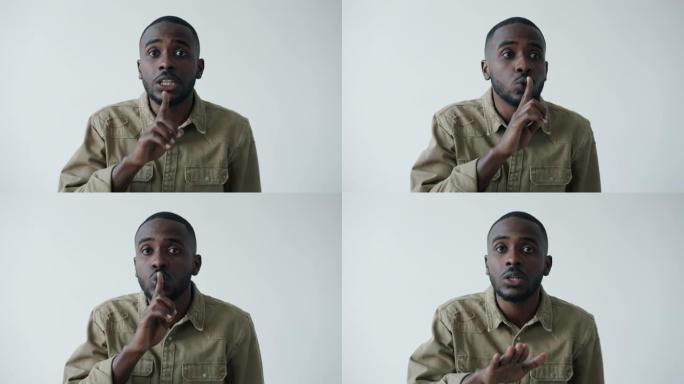 严肃的年轻非洲裔美国人要求用手指触摸嘴唇的沉默的肖像