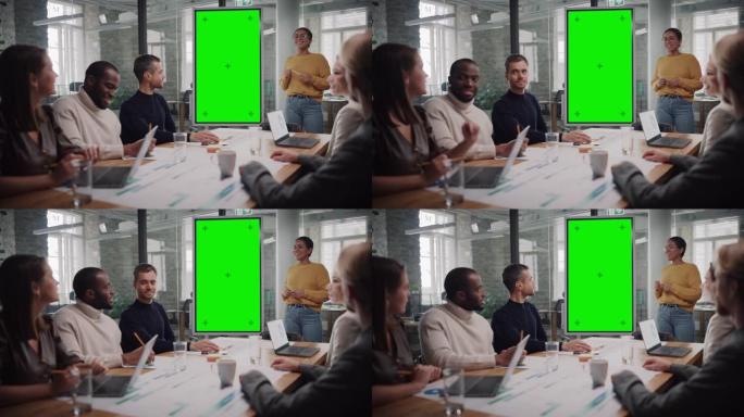 项目经理在机构会议室的一个年轻的多元化创意团队的绿屏模拟显示器上进行演示。同事们坐在会议桌后面讨论业