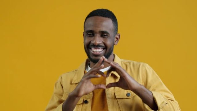 可爱的非洲裔美国男子的肖像做跳动的心脏手势和微笑
