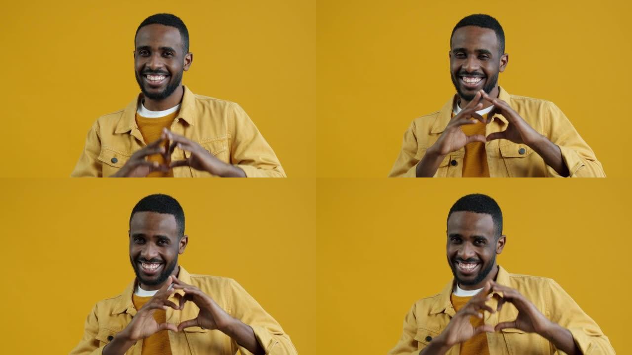 可爱的非洲裔美国男子的肖像做跳动的心脏手势和微笑