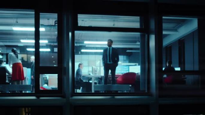 窗外的镜头: 严肃的商人走向办公室的窗户。业务经理和财务专家在后台工作。员工在移动电话上接听电话。