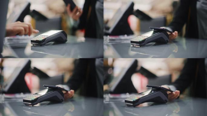 服装店: 柜台上的女人通过非接触式NFC终端购买使用智能手机付款的衣服。百货商店、购物中心、商场采购