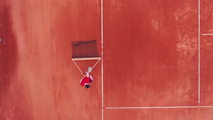 一个男人拿着网的网球场的俯视图