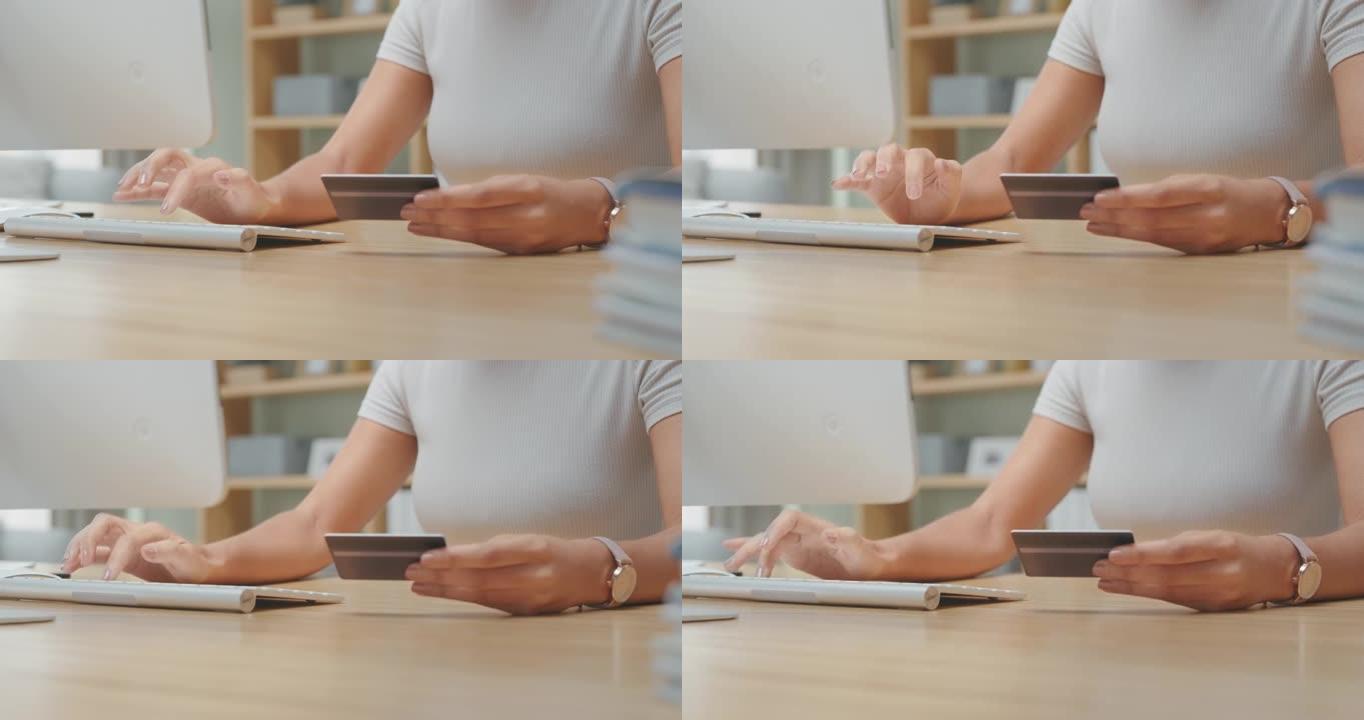4k视频片段，一名妇女在计算机上打字时拿着信用卡