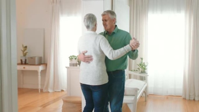 高级夫妇喜欢在家庭卧室或客厅地板上做浪漫的舞蹈。退休男子微笑，与老年妇女一起跳舞可爱的华尔兹，在房子