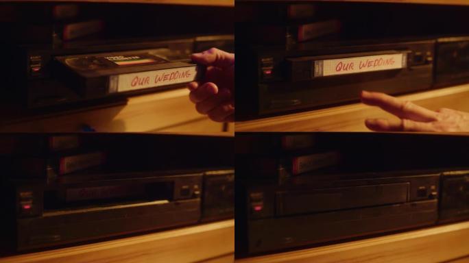 一个人在播放器中插入VHS盒式磁带的特写镜头，并带有家用摄像机的怀旧婚礼镜头。复古90年代技术概念。