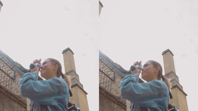 街头女性在复古数码相机上拍照的垂直视频发布到社交媒体