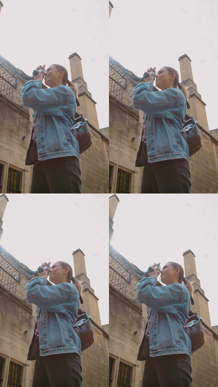 街头女性在复古数码相机上拍照的垂直视频发布到社交媒体
