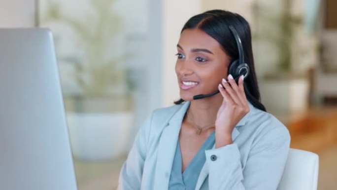 在咨询客户服务和销售支持时使用耳机的呼叫中心电话营销代理。自信的年轻女商人在操作服务台时微笑着，看上