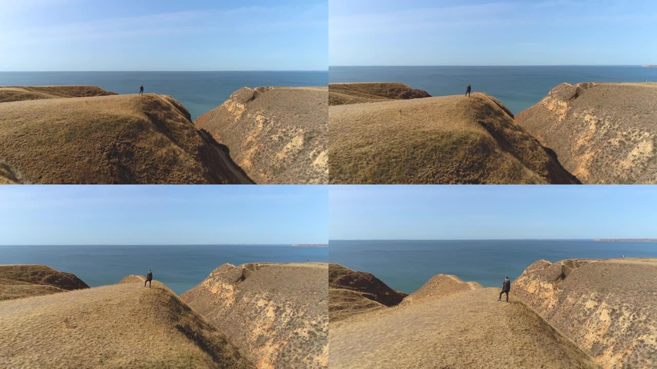 那个背着背包的家伙站在山顶上，靠着海景