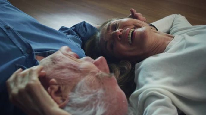 可爱的幸福成熟夫妇在一起享受时光的电影拍摄，躺在家里的地板上，互相爱抚。概念: 爱情、家庭、婚姻、幸