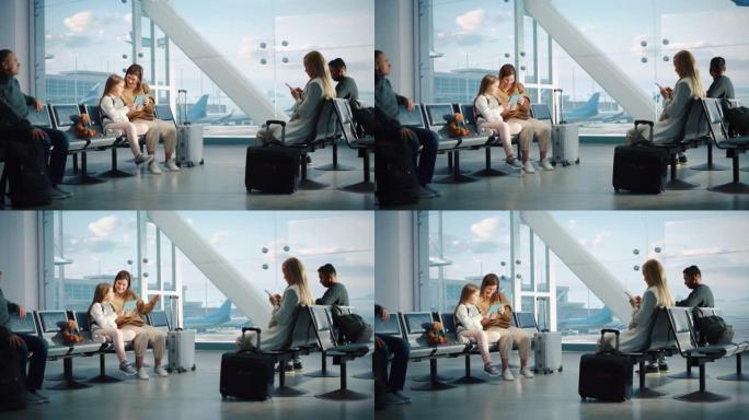 机场航站楼: 可爱的母亲和小女儿等待他们的家人度假航班，在数字平板电脑上玩教育游戏。坐在飞机枢纽登机