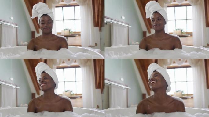快乐的非洲裔美国迷人的女人在浴室的泡沫浴缸中放松