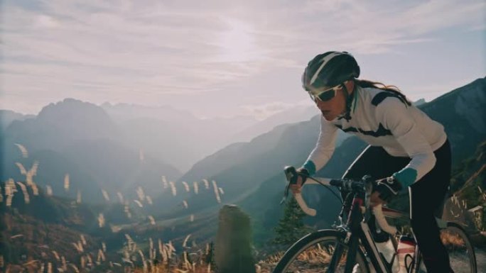 坚定的骑自行车者在阳光明媚的山脉上坡骑自行车