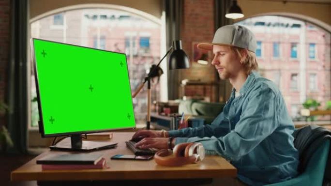 年轻英俊的男人在家工作，在带有绿屏模拟显示的台式计算机上。学生做家庭作业，为考试而学习。从大窗户可以