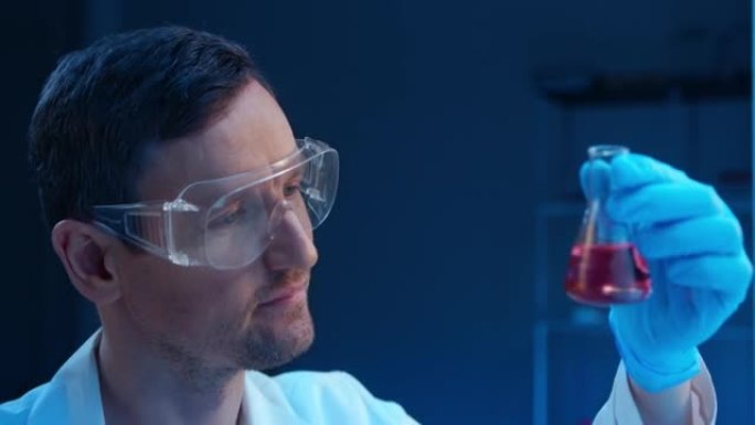 一位年轻的化学家在实验室烧瓶中查看化学反应的结果，然后将其输入他面前的计算机中