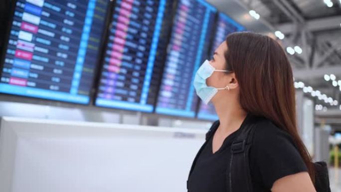东南亚妇女在等待在机场度假时看着智能手表