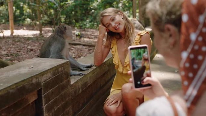 旅游女人使用智能手机在野生动物动物园与猴子合影留念，分享旅行冒险
