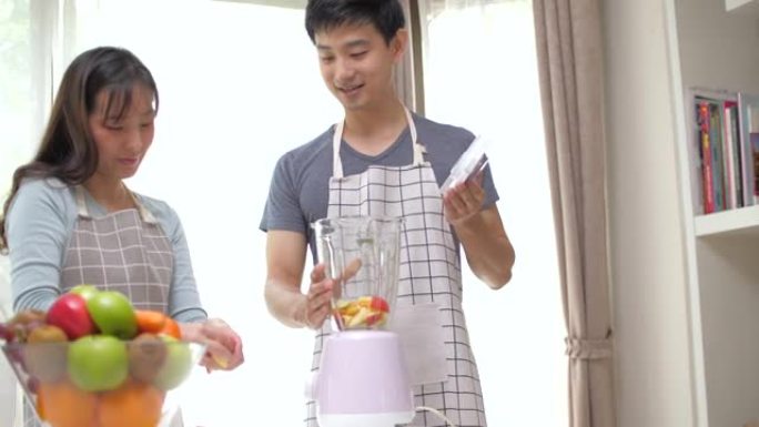 亚洲夫妇准备蔬菜和水果，并使用榨汁机进行冷榨果汁