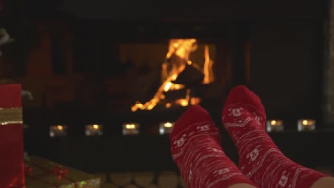 特写: 穿着红色圣诞袜的女性脚在壁炉前热身