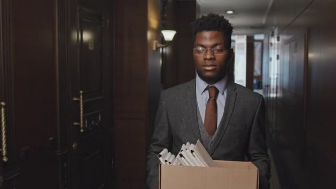 非裔美国商人带着一盒文件离开办公室