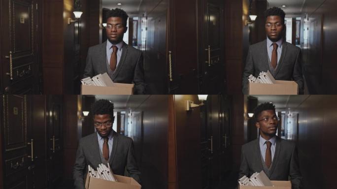 非裔美国商人带着一盒文件离开办公室