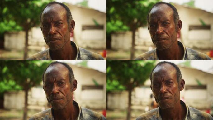真实的老非洲人的肖像认真地看着相机模糊的背景。目光坚定的老爷子生活在乡村，让传统永存