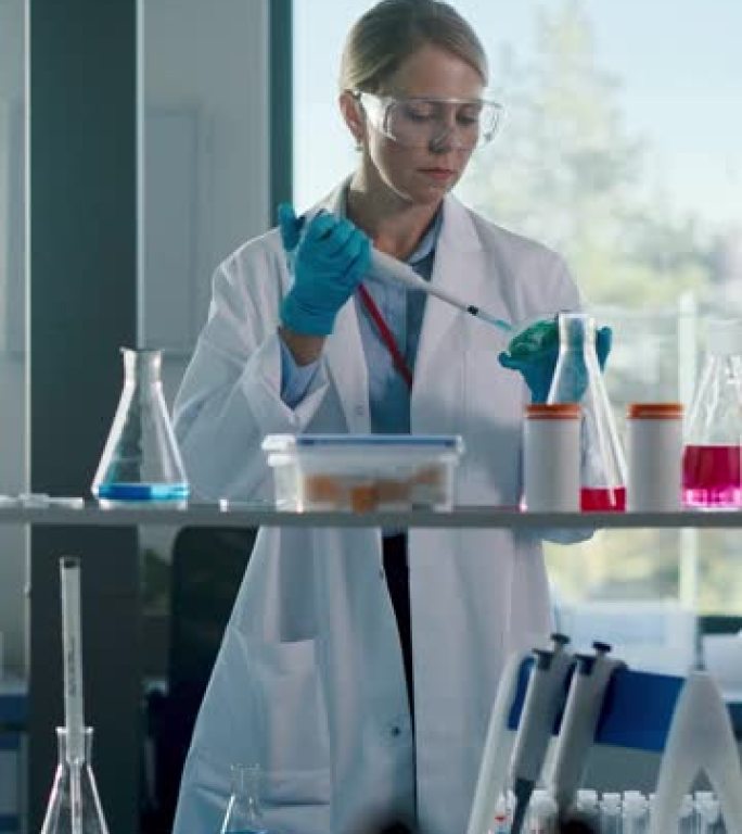 垂直视频: 美丽的女医学家穿着白大褂和安全眼镜，在检查样品时使用微量移液器。创新、实验药物研究、实验