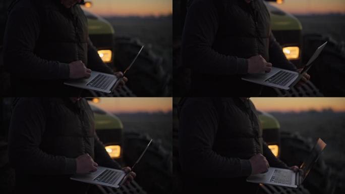 男性农民在日出时在田间拖拉机上使用笔记本电脑