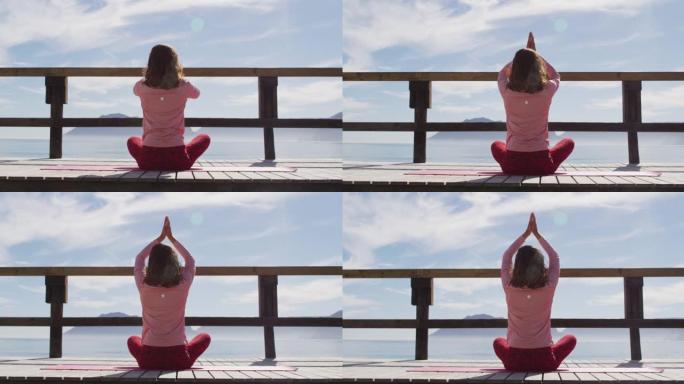 混血女子在户外练习瑜伽，坐在海边冥想的后视图