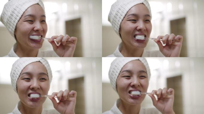 亚洲妇女拿着牙刷刷牙照镜子在浴室