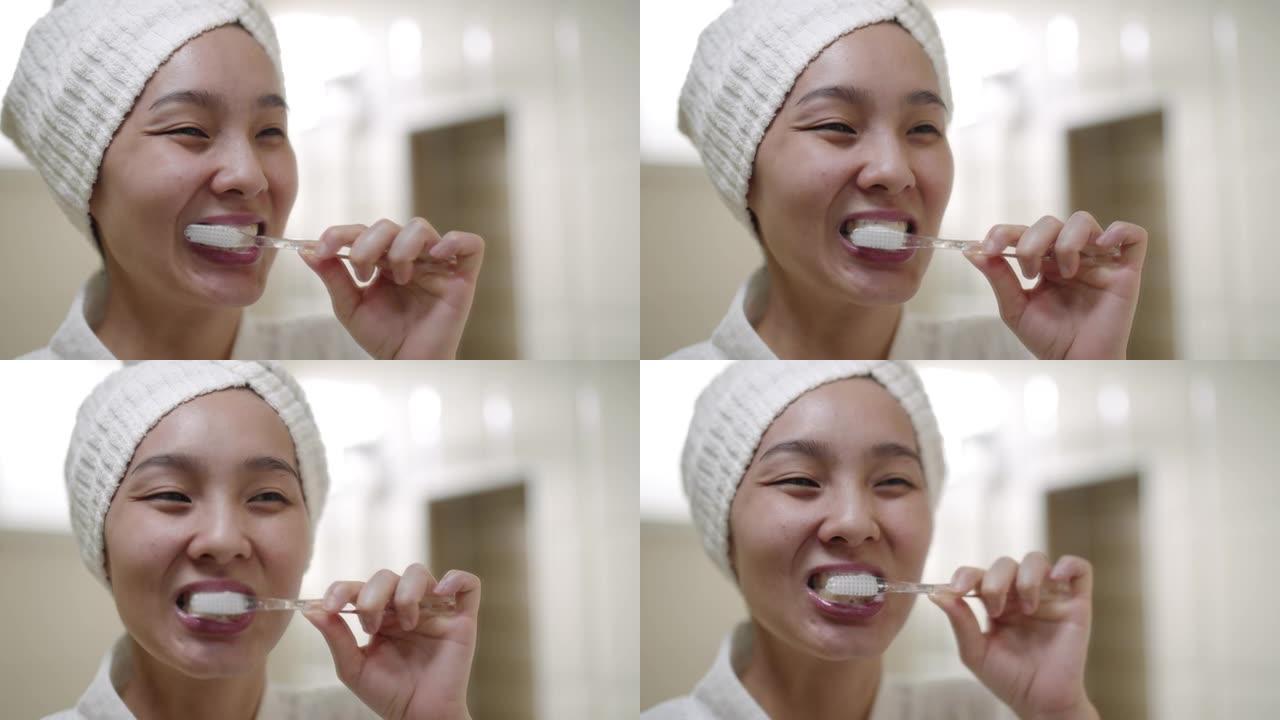 亚洲妇女拿着牙刷刷牙照镜子在浴室
