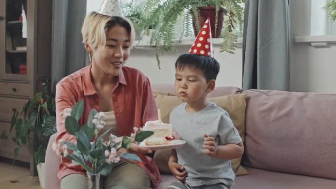 3岁亚洲男孩在生日蛋糕上吹蜡烛