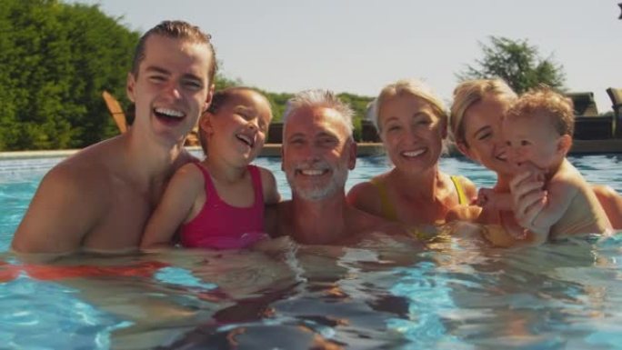 暑假在游泳池放松的多代家庭与男婴的肖像