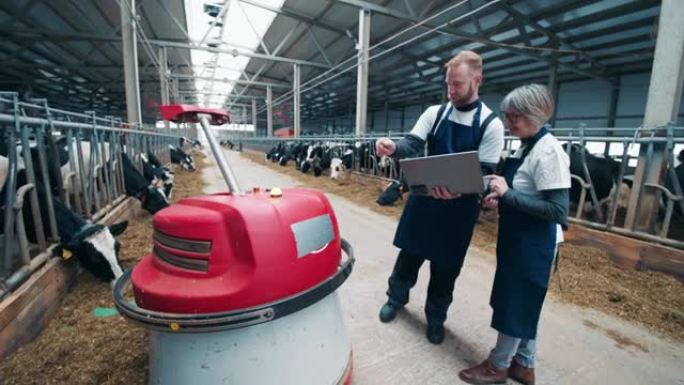 两名cowhouse工人正在管理一个机器人饲料推进器